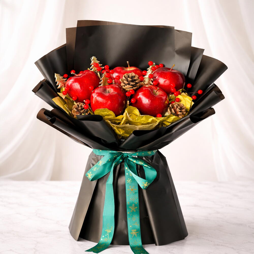 Bouquet of red apples and decorative elements wrapped in black paper with a green ribbon on a white background