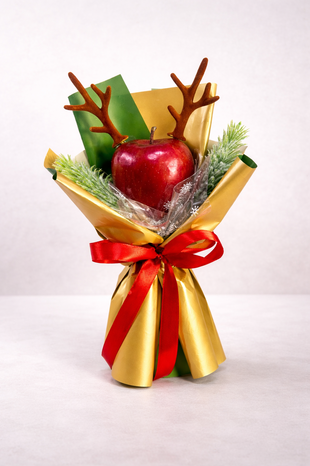 Bouquet of apple wrapped in gold paper with a red ribbon on a white background