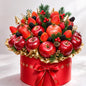 Decorative fruit and berry arrangement in a red box with a gold bow on a white background
