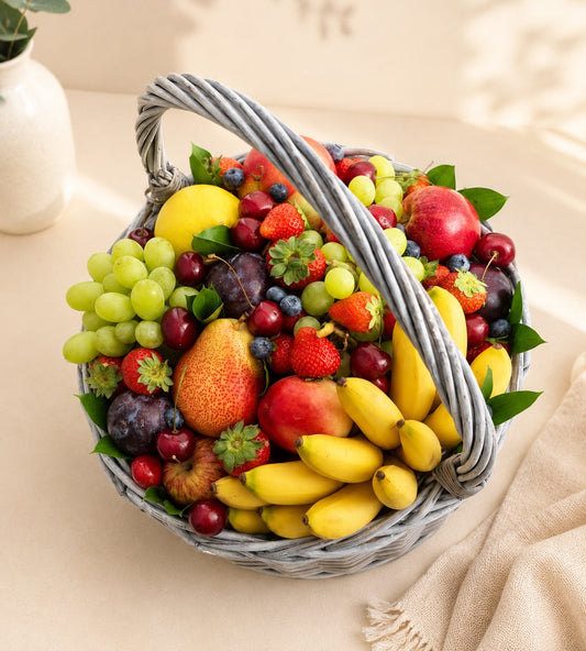 Luxury fresh fruit basket featuring grapes, strawberries, cherries, blueberries, pears, apples, plums, and bananas in an elegant wicker basket, perfect for healthy gifting in Dubai