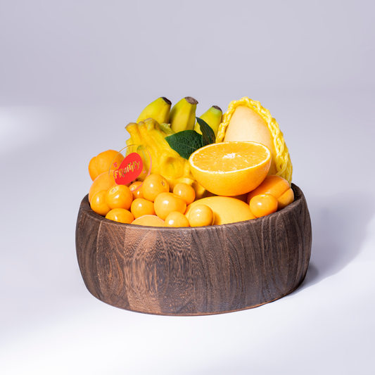 Premium yellow fruit bowl featuring melon, oranges, bananas, golden berries, star fruit, and seasonal fruits in an elegant wooden bowl, perfect for healthy gifting in Dubai