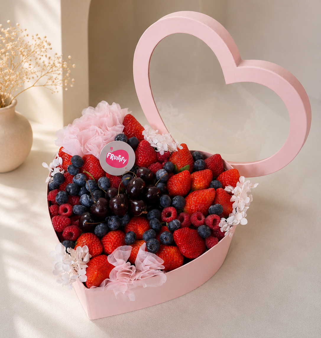 Luxury heart-shaped berry gift box with fresh strawberries, blueberries, raspberries, cherries, and floral accents in pink packaging for gifting in Dubai.