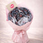 Bouquet of assorted berries wrapped in pink paper with a bow on a light pink background