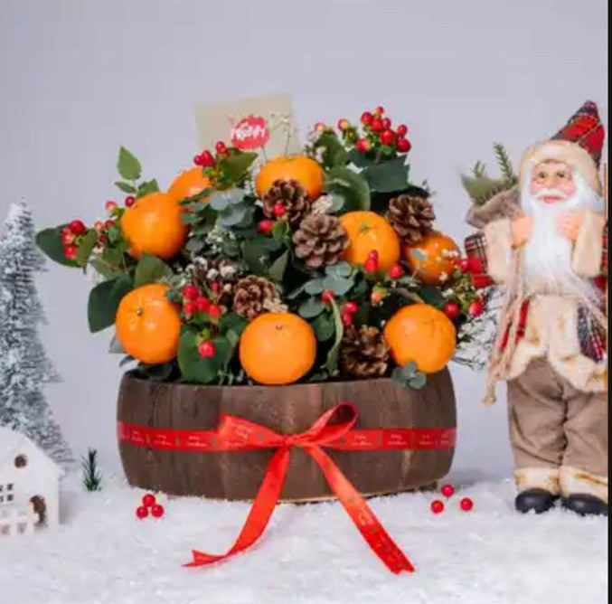 Decorative basket with oranges, berries, and pine cones next to a Santa Claus figure on a snowy background.