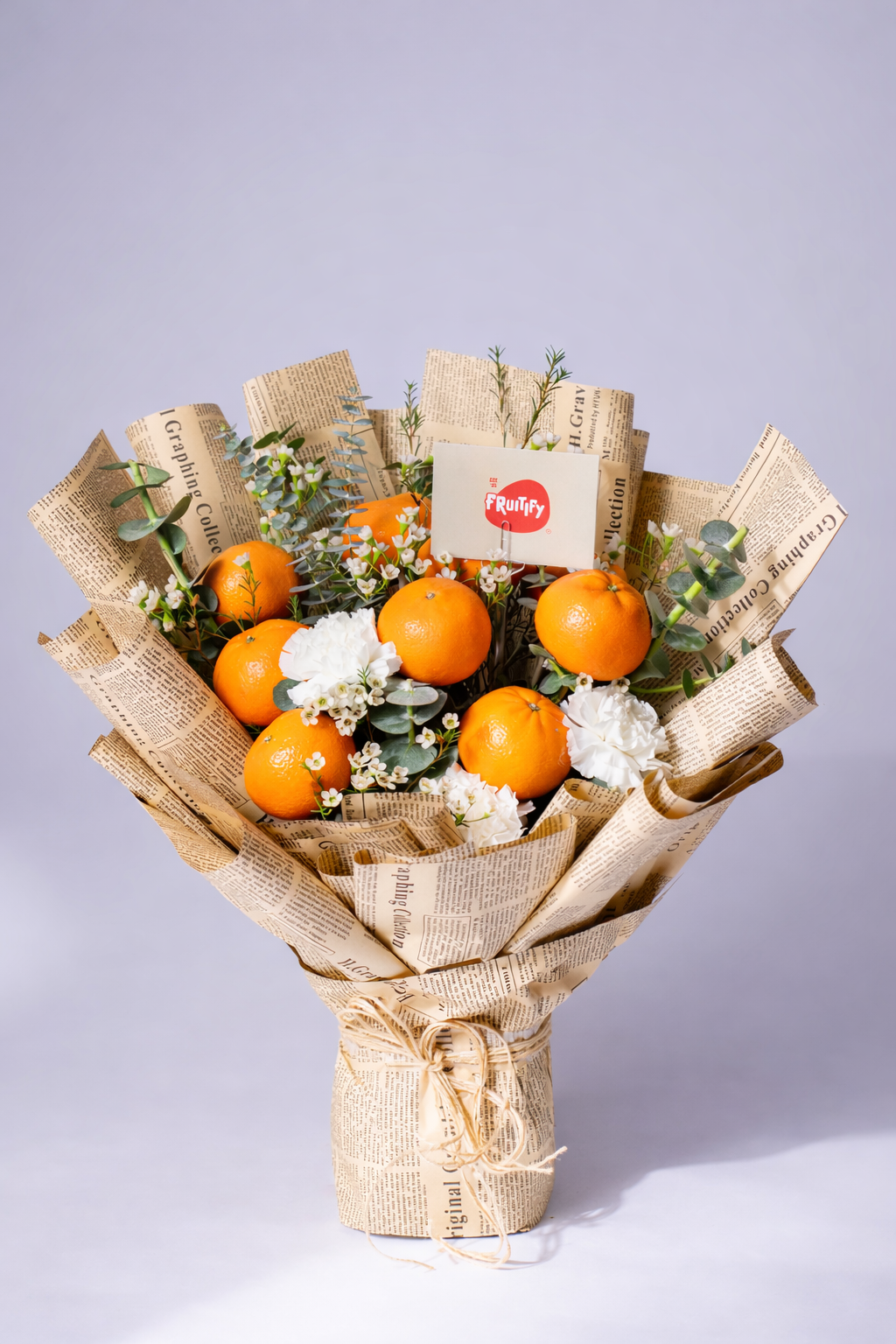 Bouquet of oranges and flowers wrapped in brown paper with a visible brand label on a light gray background.