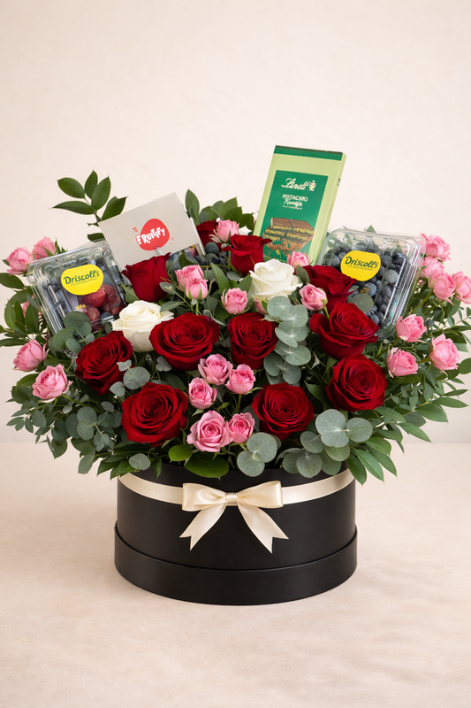 Floral arrangement with red and pink roses in a black box on a light background