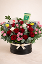 Floral arrangement with red and pink roses in a black box on a light background