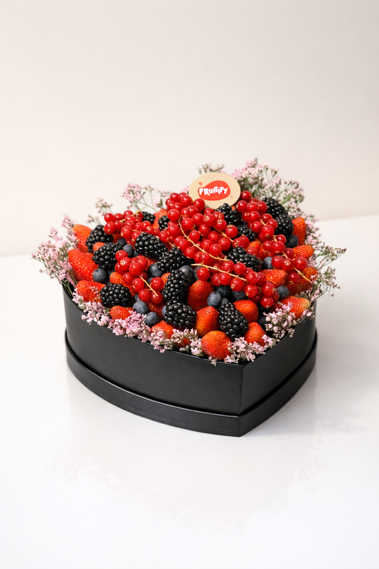 Heart-shaped arrangement of berries and flowers on a white background