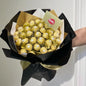 Bouquet of Ferrero Rocher chocolates wrapped in gold paper and black ribbon, held by a person.