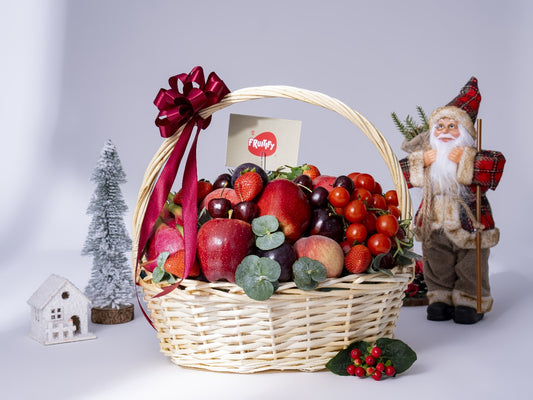 Fruit basket with a Santa figurine and Christmas decorations on a light background