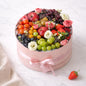 Fruit and flower arrangement in a pink box on a white background