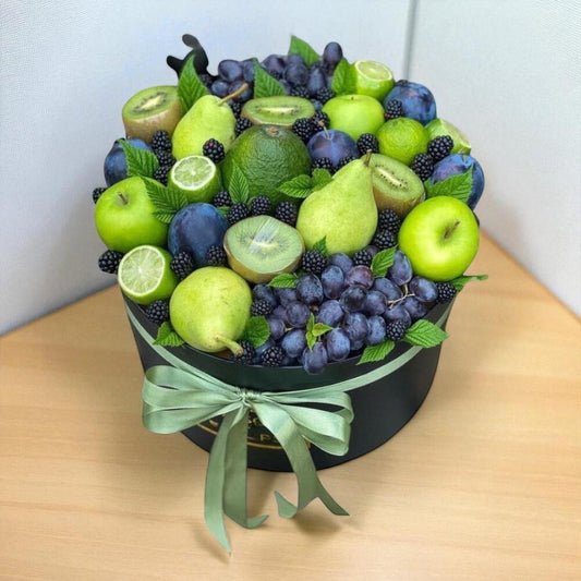 Fruit arrangement in a black box with green ribbon on a wooden surface