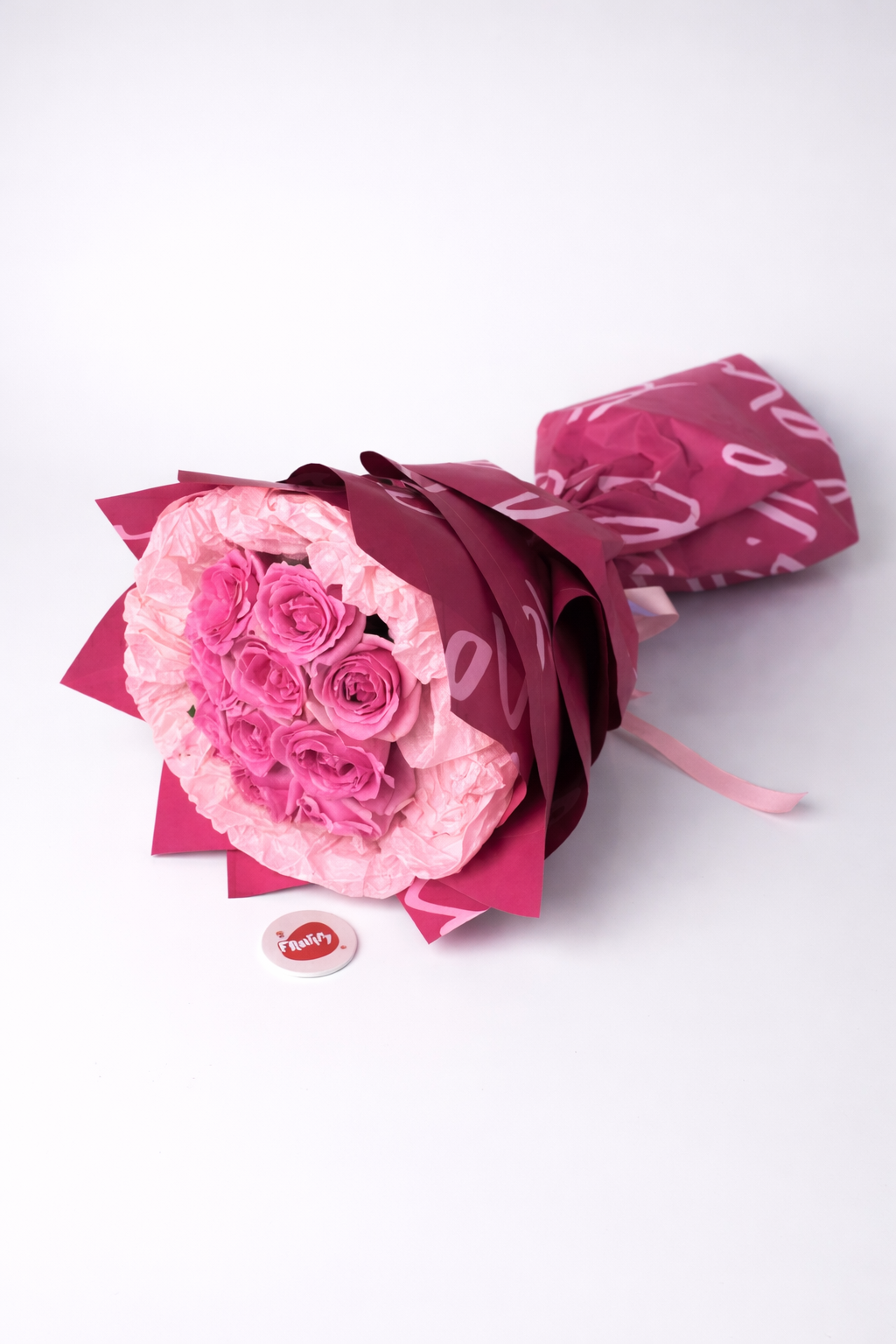 Bouquet of pink roses wrapped in red paper on a white background