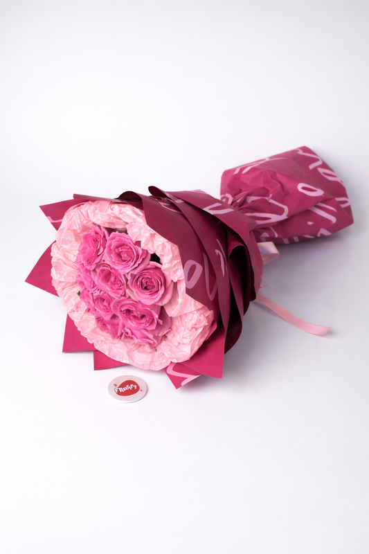 Bouquet of pink roses wrapped in red paper on a white background