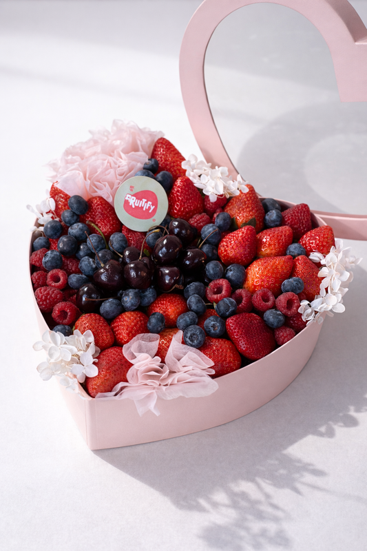 Heart-shaped box filled with a berry arrangement on a light background