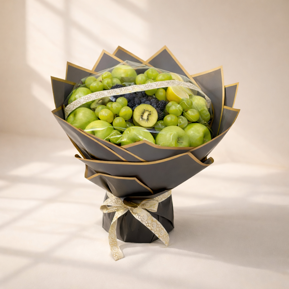 Bouquet of green fruits wrapped in black paper with a gold ribbon on a light background