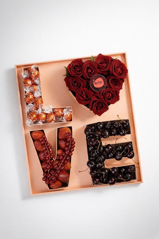 Gift set with 'LOVE' lettering made of fruits and a heart-shaped rose arrangement on a white background.