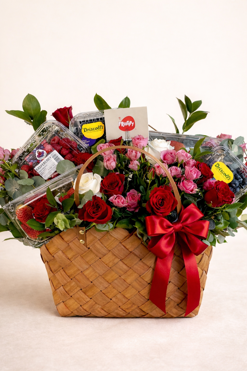 Gift basket with flowers, snacks, and a red ribbon on a white background