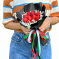 Person holding a bouquet of strawberries with decorative ribbons on a white background