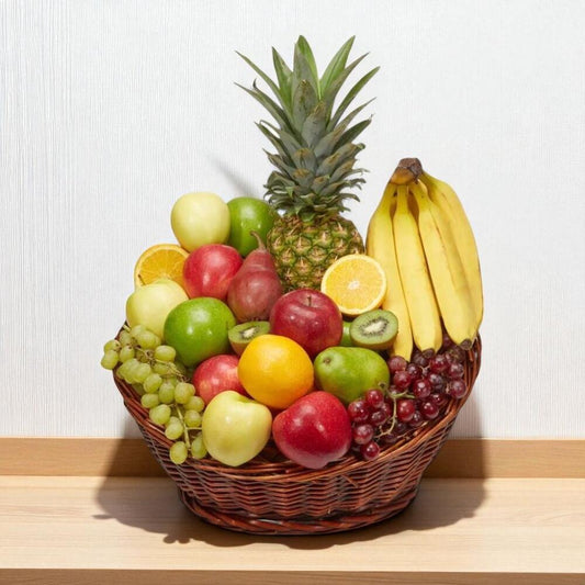 Fruit basket with a pineapple, bananas, apples, oranges, and grapes on a light background.