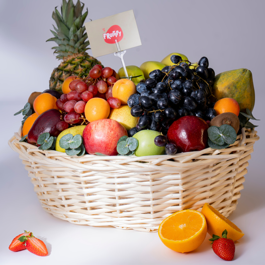 Fruit basket with a variety of fruits including apples, oranges, and grapes, on a white background.