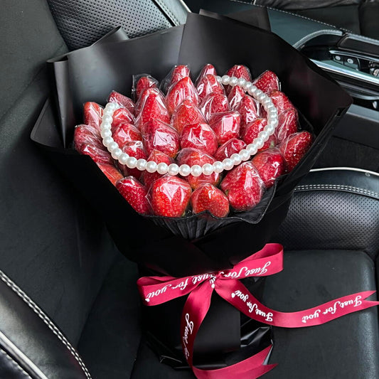 Bouquet of red strawberries with a pearl necklace wrapped in black paper and a red ribbon inside a car.
